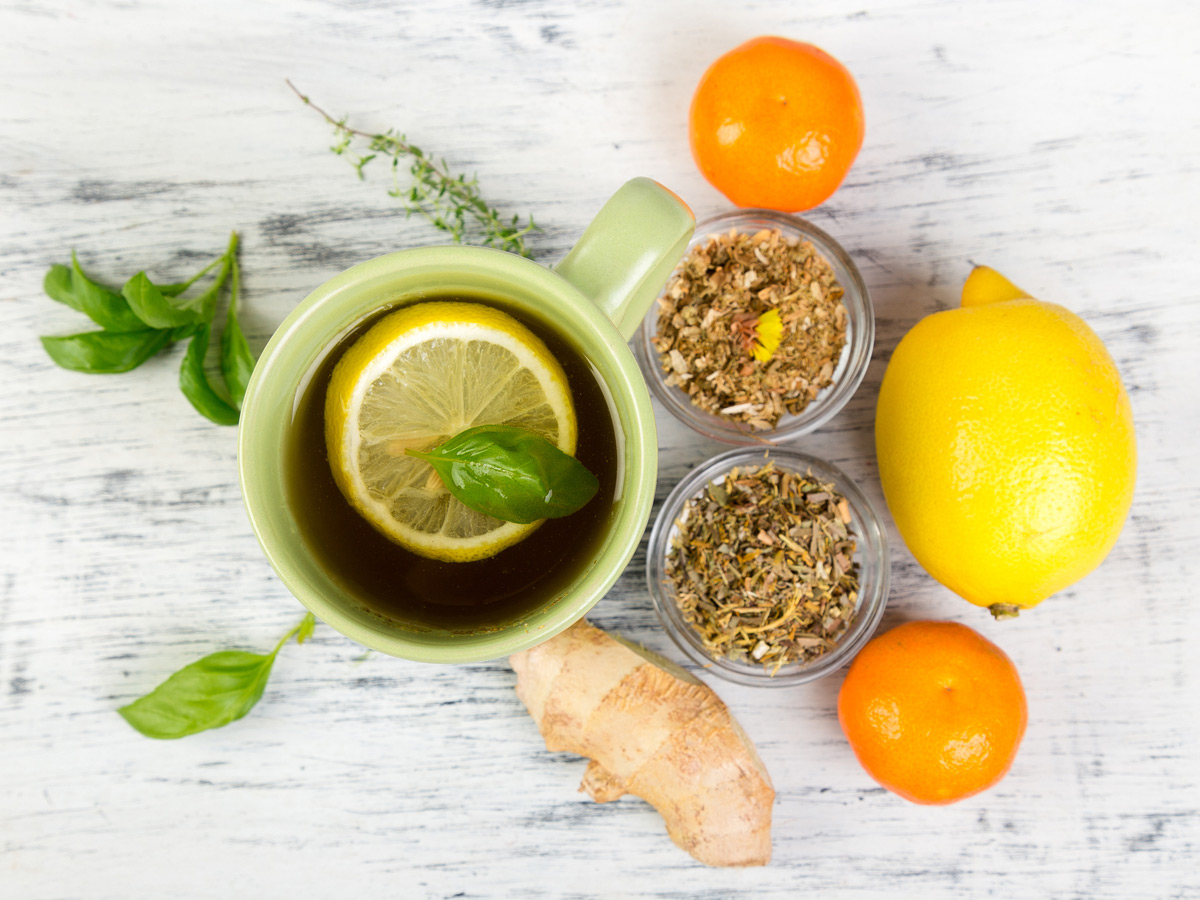 Common cold remedies of citrus fruits, ginger and herbal teas alongside a hot lemon and honey drink